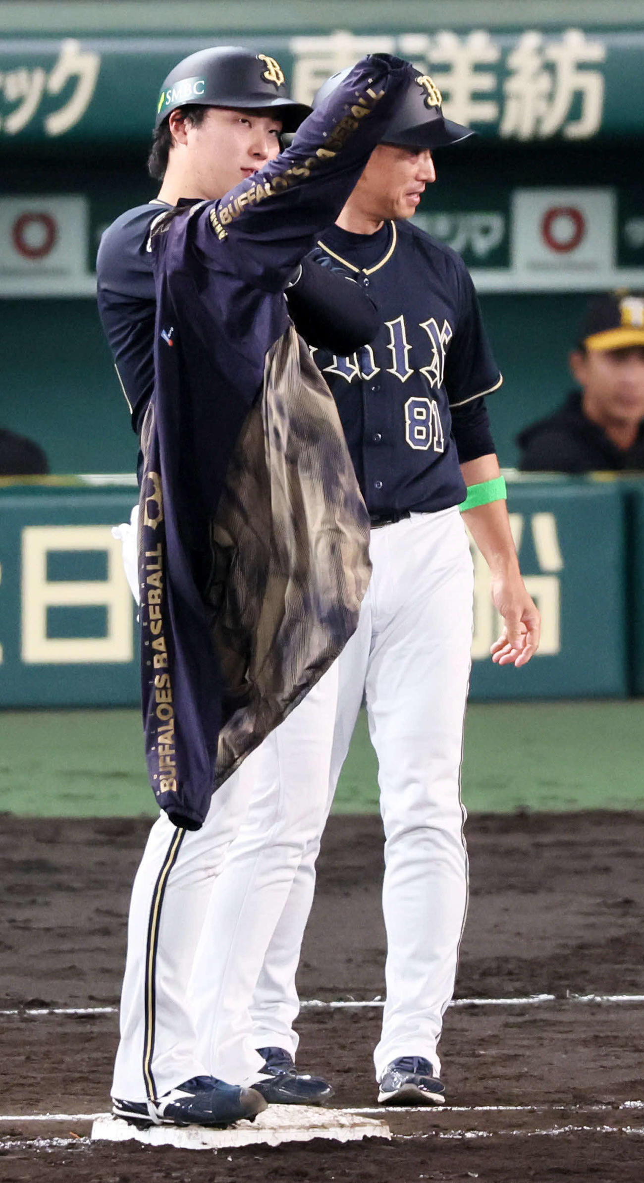 阪神対オリックス　5回表オリックス1死一塁、ウインドブレーカーを着るのに苦戦する一塁走者東（中央）。右は田口コーチ（撮影・加藤哉）