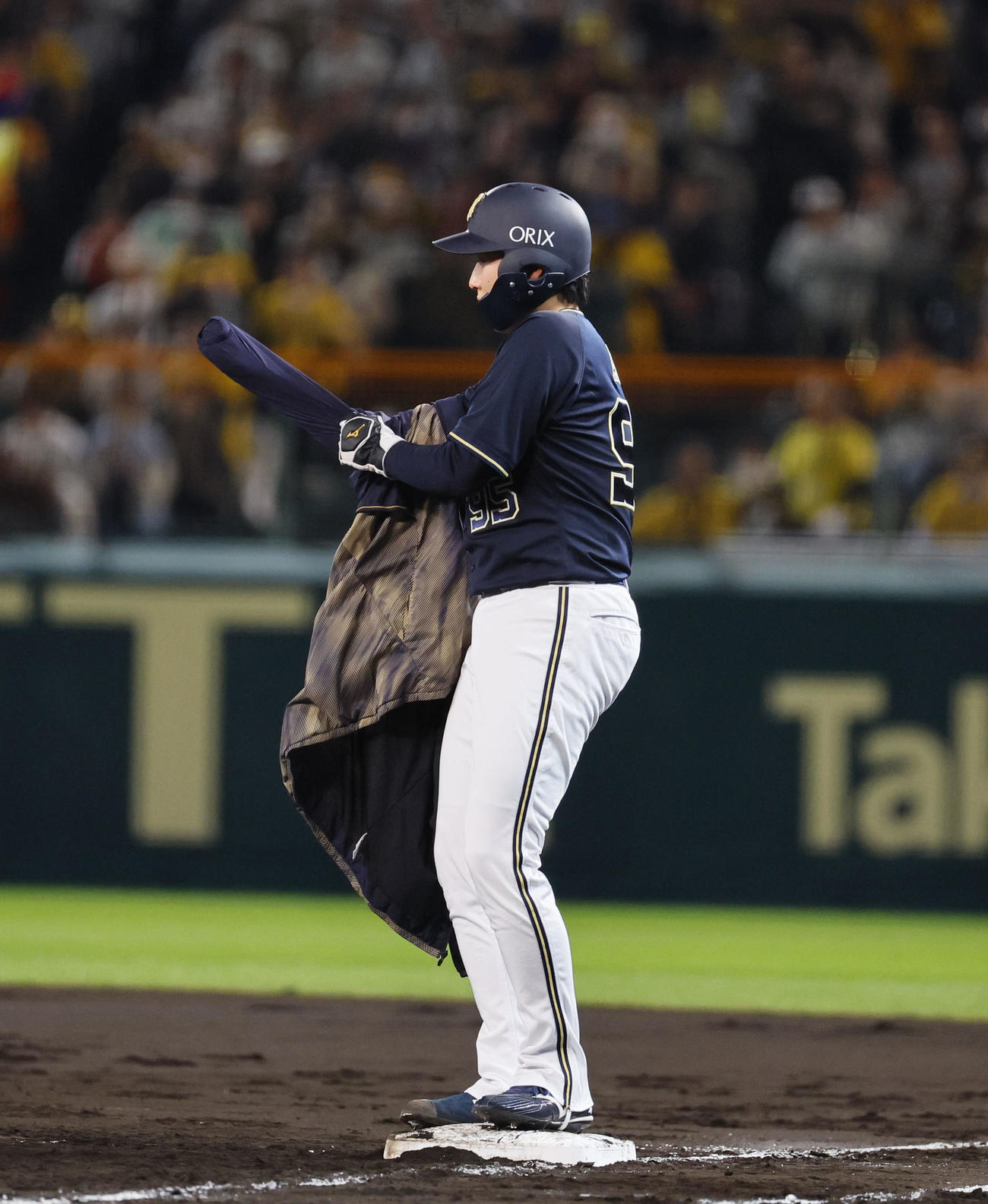 阪神対オリックス　5回表オリックス1死一、二塁、ウインドブレーカーを着るのに苦戦する一塁走者東（撮影・藤尾明華）