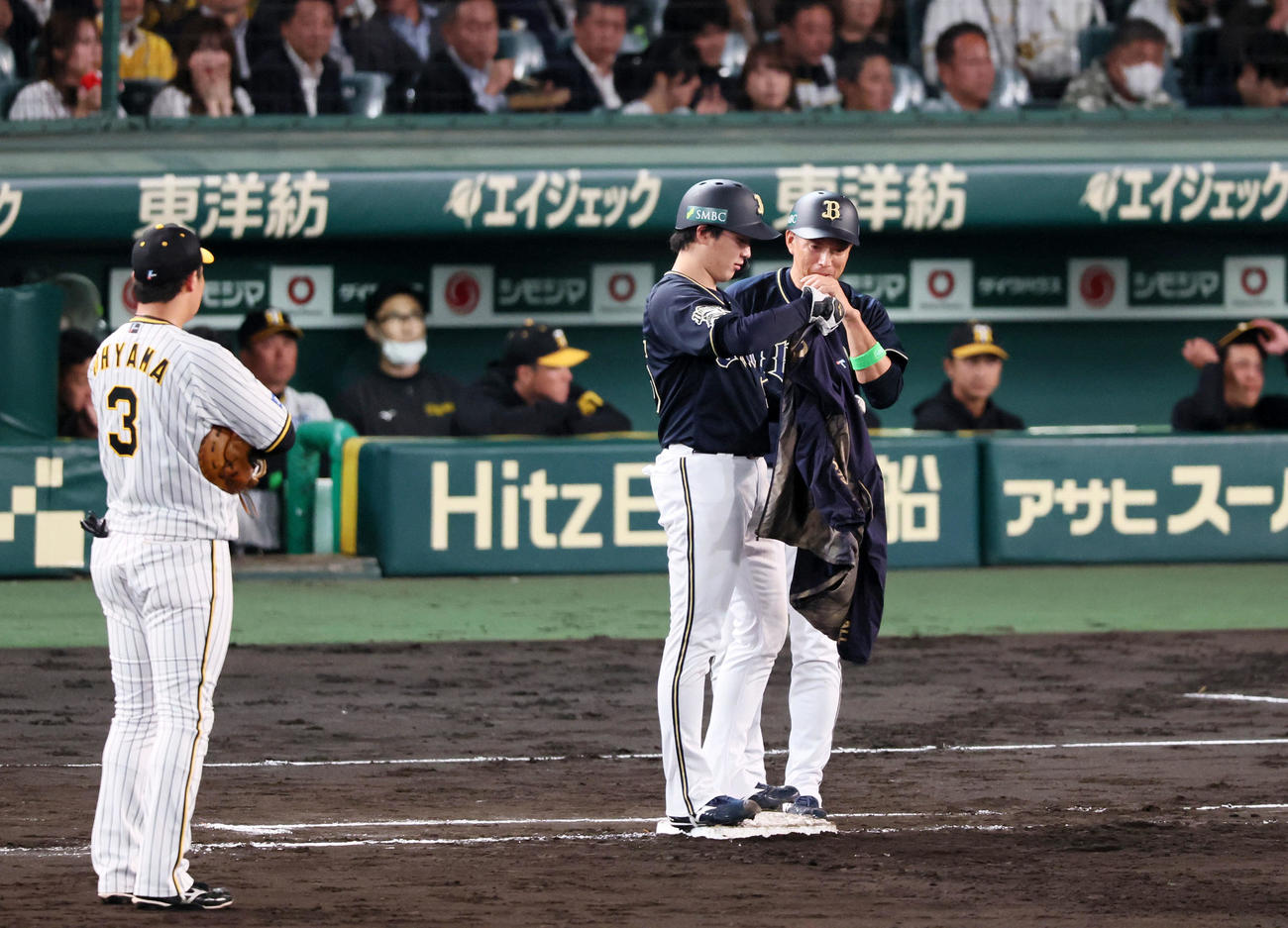 阪神対オリックス　5回表オリックス1死、一塁走者となり上着に袖を通そうとする東だが…。右は田口コーチ（撮影・加藤哉）