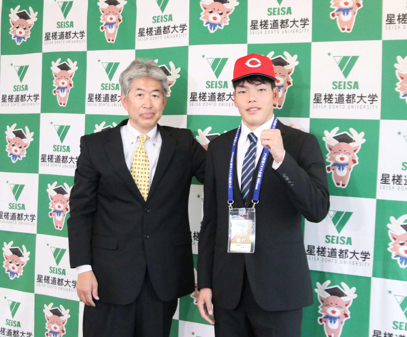 近藤スカウト（左）から帽子をかぶせてもらい、笑顔をみせる広島ドラフト3位の星槎道都大・滝田（撮影・山崎純一）