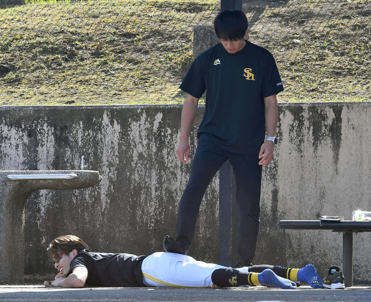 400メートル走の合間に、西田広報（上）にマッサージをしてもらう周東（撮影・岩下翔太）