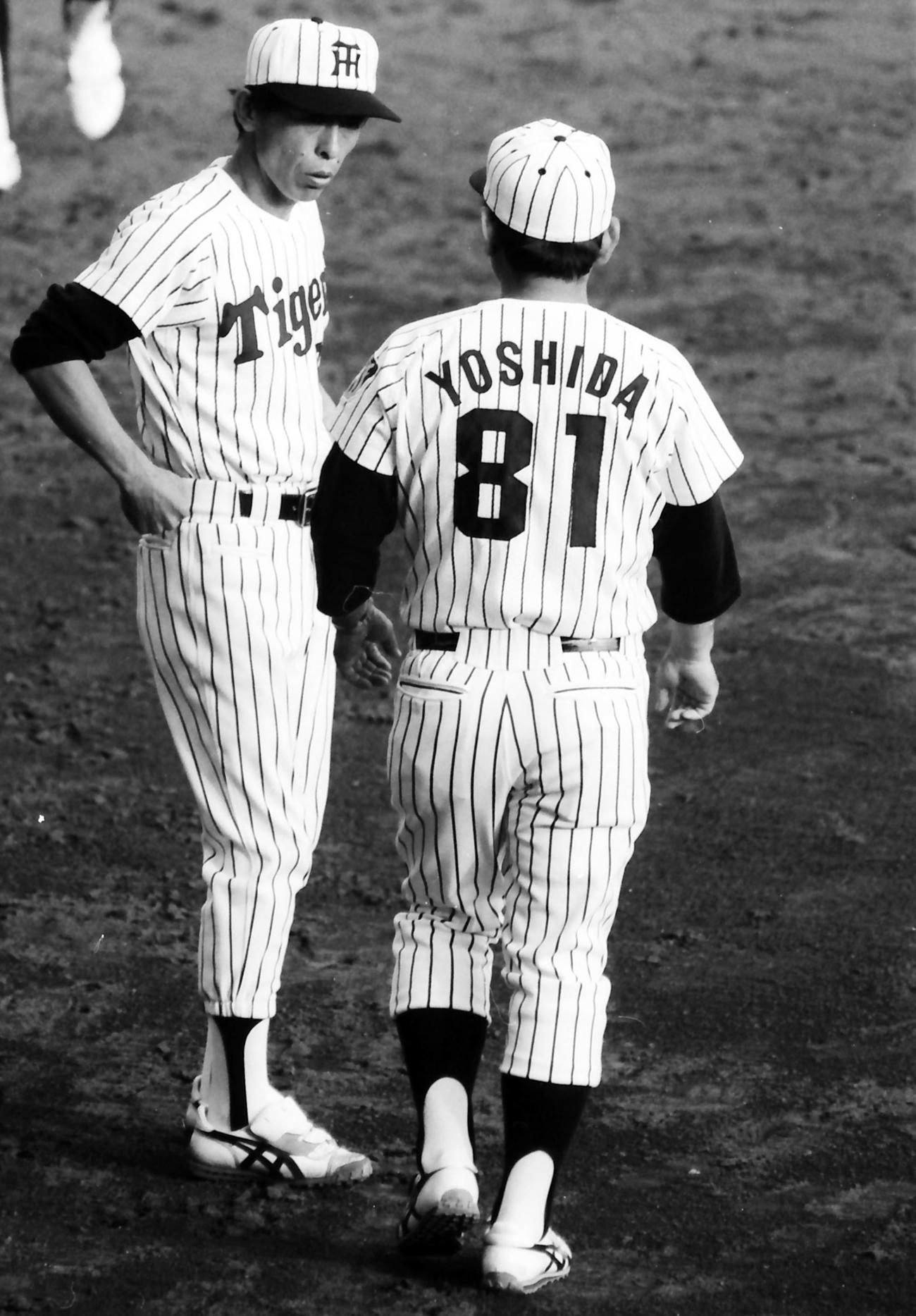 1985年10月31日、日本シリーズ第5戦　阪神対西武　ベンチ前で吉田義男監督（右）と話す一枝修平コーチ