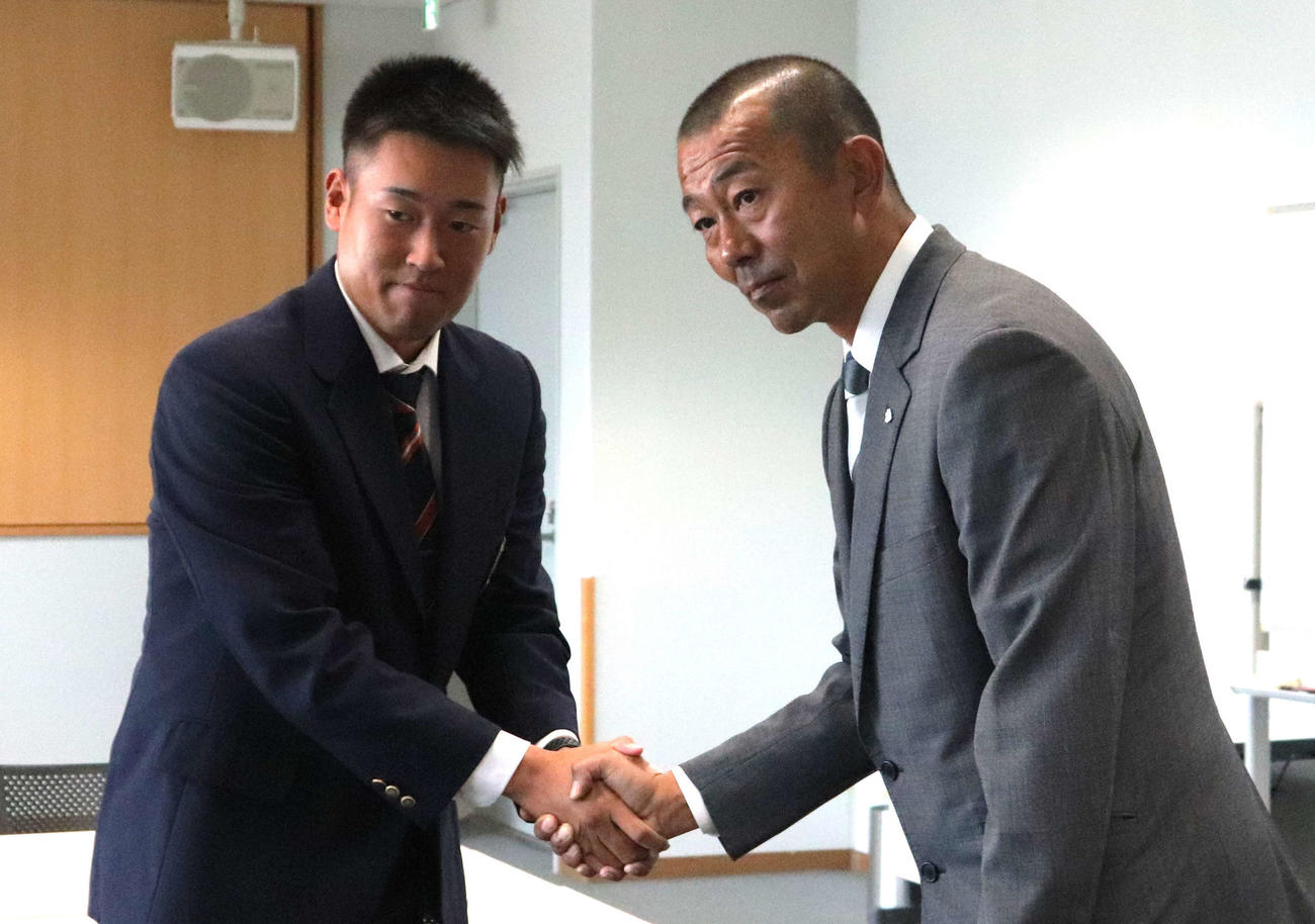 後藤光貴担当スカウトと握手をする、西武ドラフト2位の大商大・上田大河（撮影・中島麗）