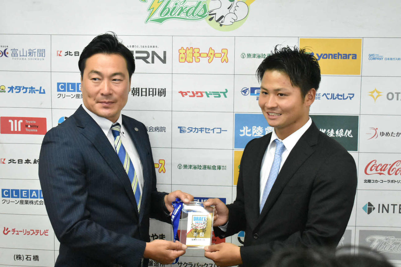 指名あいさつで阪神筒井スカウト（左）からドラフト会議のパスを受け取る日本海L富山・松原（富山球団提供）