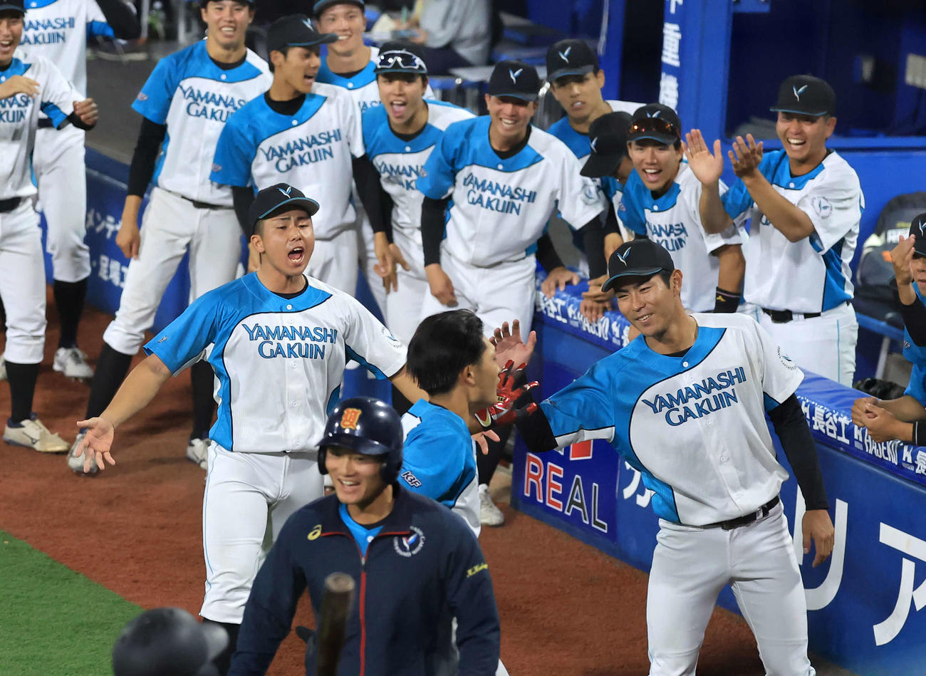 山梨学院大対創価大　5回表山梨学院大1死、小貝（手前）がソロ本塁打を放ち、笑顔で迎える宮崎（右）ら山梨学院大ナイン（撮影・浅見桂子）