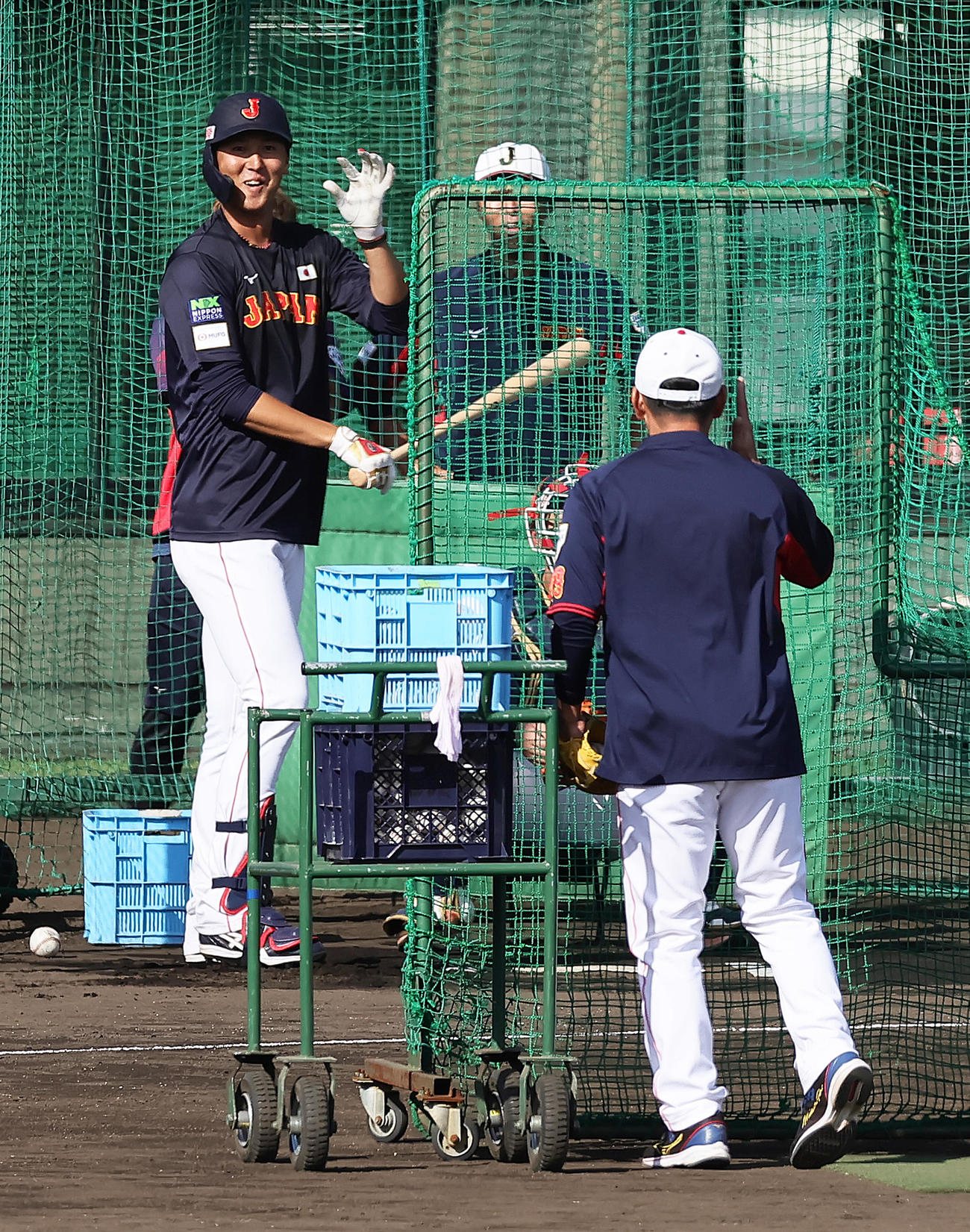 打撃投手を務める井端監督（手前）に笑顔を見せる秋広（撮影・足立雅史）