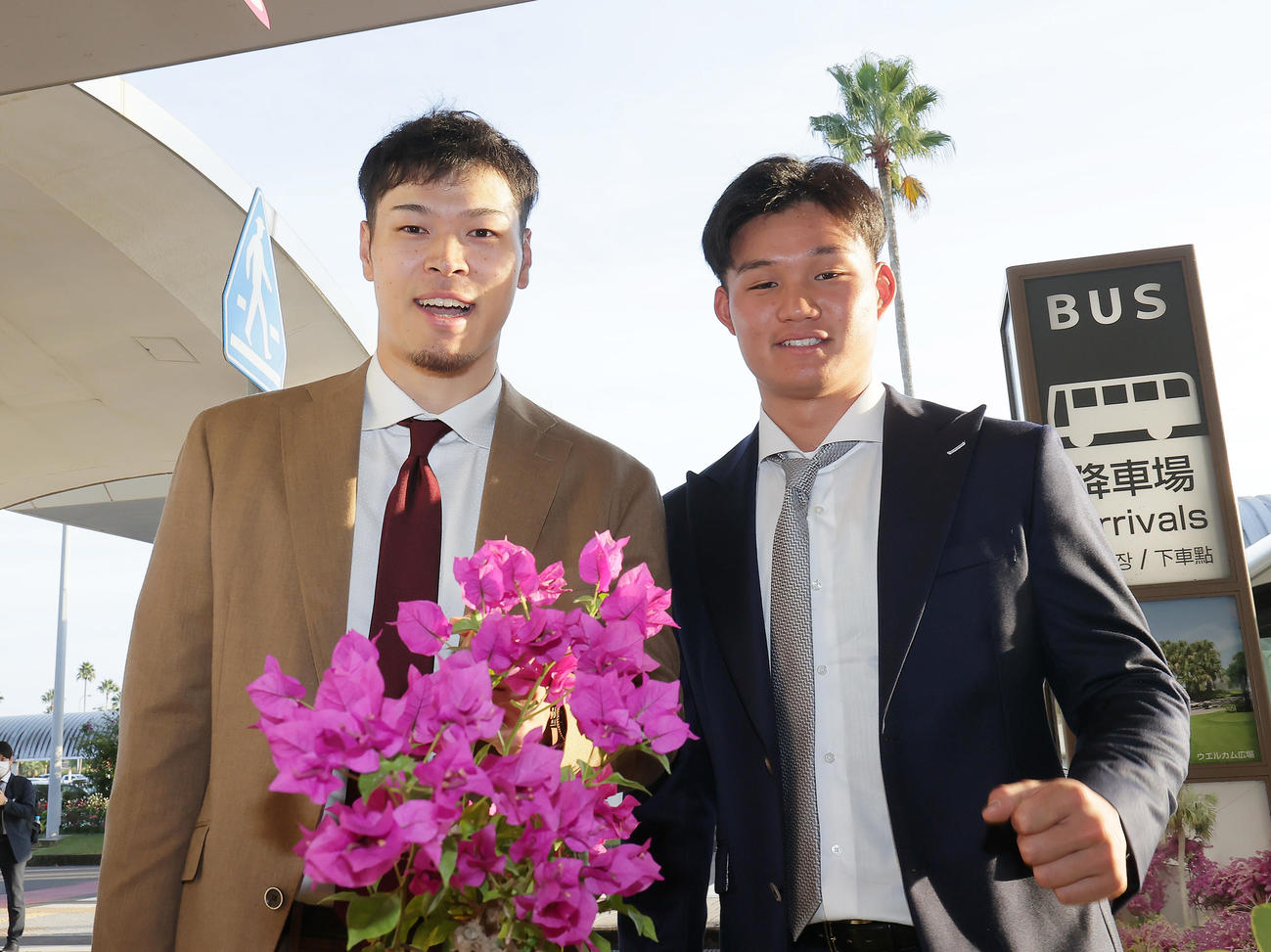 宮崎に到着し、ブーゲンビリアの花を前に笑顔を見せる阪神の佐藤輝明（左）と森下（撮影・足立雅史）