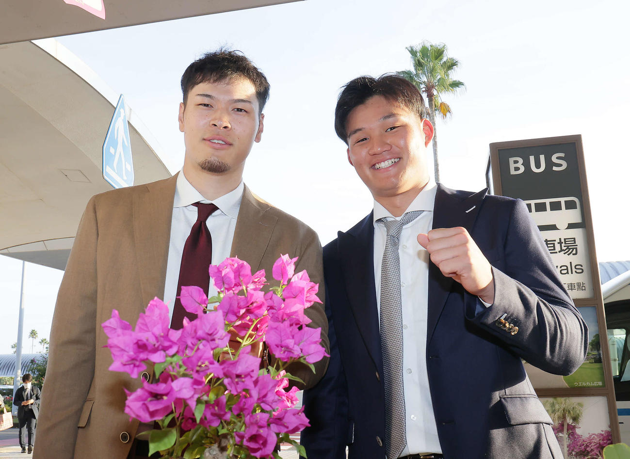宮崎に到着し、ブーゲンビリアの花を前に笑顔を見せる阪神の佐藤輝（左）と森下（撮影・足立雅史）