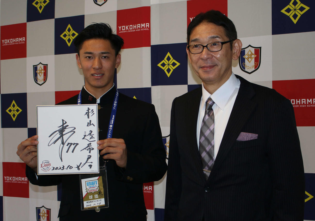 西武から指名あいさつを受け、松井稼頭央監督のサイン色紙に笑顔を見せるドラフト3位の横浜・杉山遥希投手（左、右は横浜・葛蔵造校長）（撮影・木下大輔）