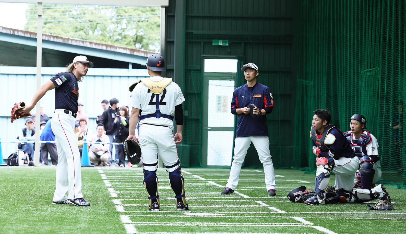 ブルペン投球を終えた今井（左端）は捕手陣らと会話を交わす。左から1人おいて古賀、吉見投手コーチ、坂倉、石橋（撮影・足立雅史）