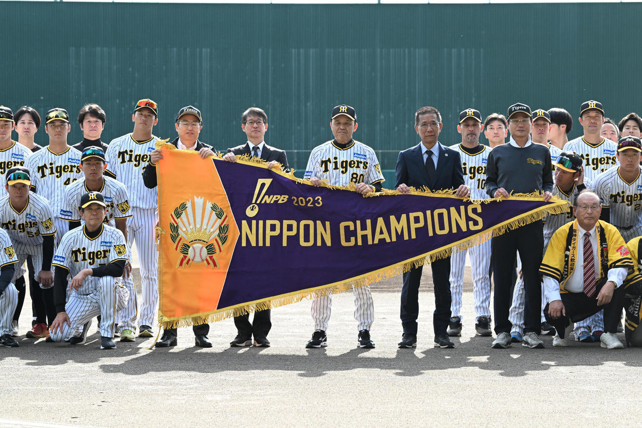 歓迎セレモニーで日本一のチャンピオンフラッグを手に記念撮影を行う岡田彰布監督ら阪神ナインと関係者（撮影・前岡正明）