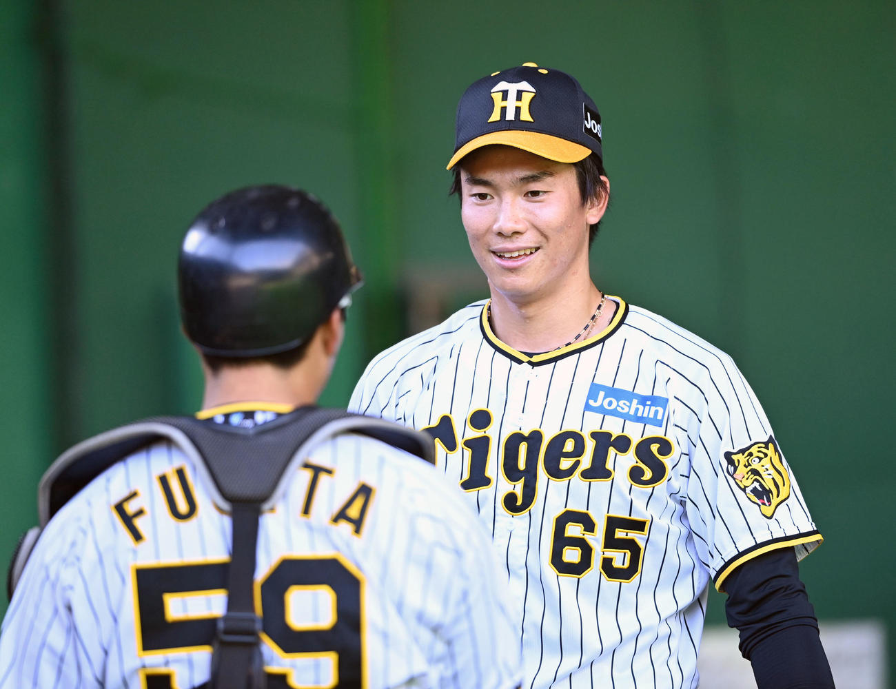 ブルペンでの投球練習後、藤田（左）と笑顔で話す湯浅（撮影・前岡正明）