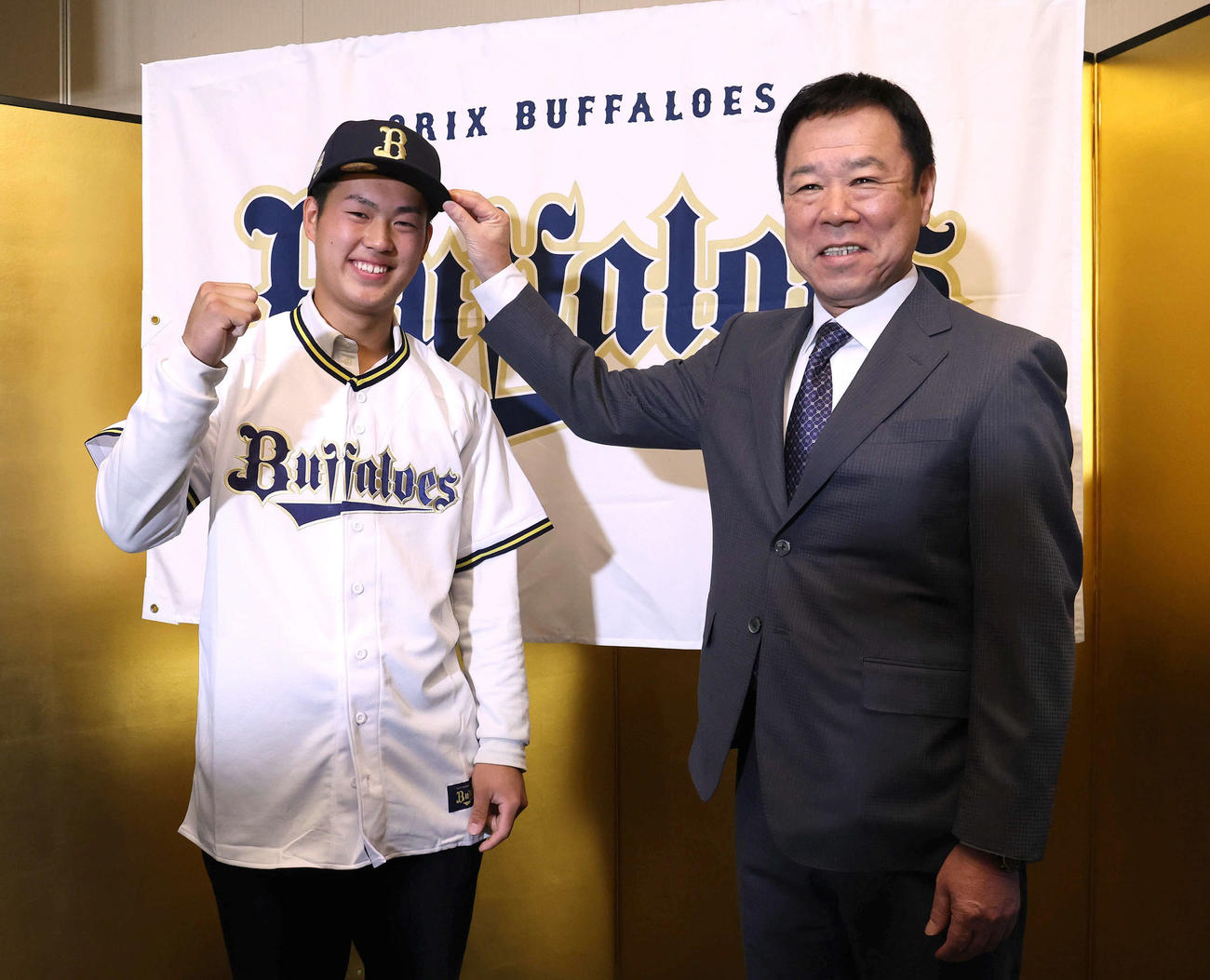 オリックスとの仮契約を終え、福良GM（右）から帽子をかぶせてもらいガッツポーズするドラフト4位の報徳学園・堀（撮影・白石智彦）