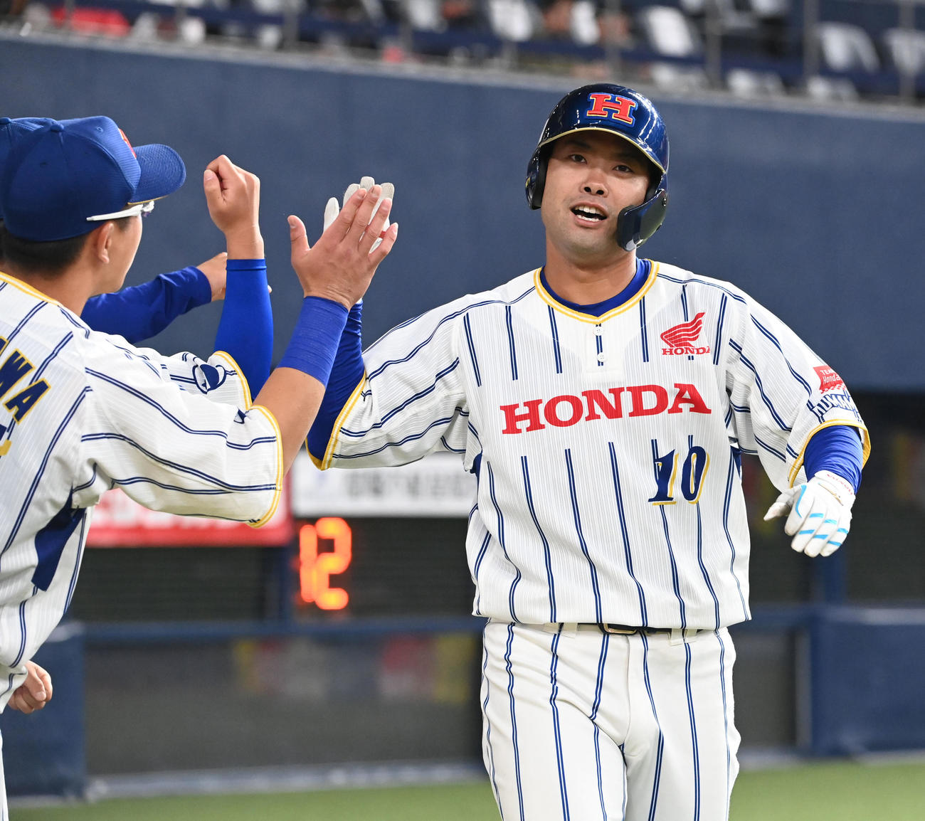 Honda熊本対トヨタ自動車　2回表Honda熊本無死、左越えソロ本塁打を放ちナインとタッチする石井（撮影・和賀正仁）