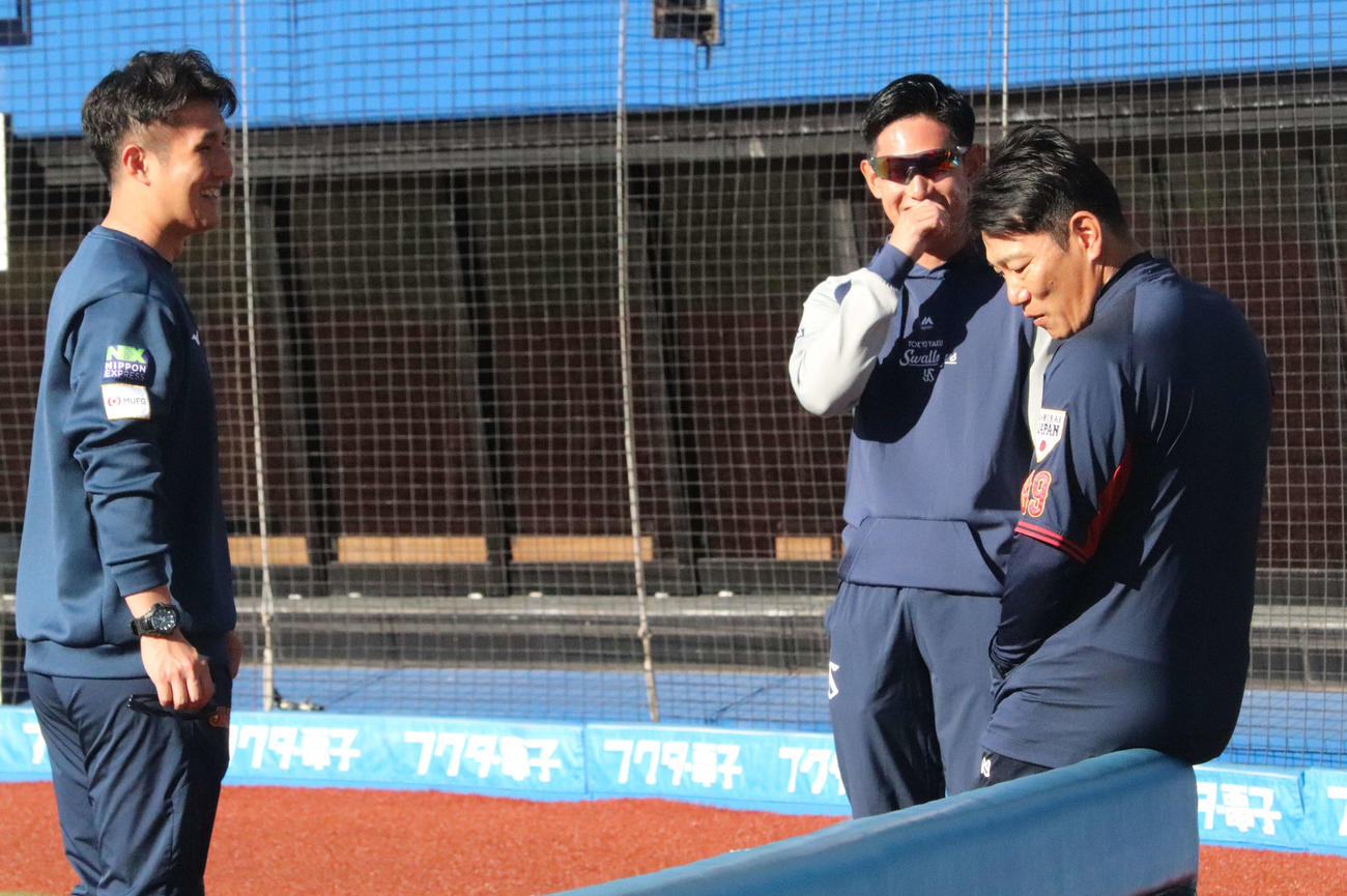 スタッフと談笑しながら侍ジャパンの投手練習を見守る井端監督（右）（撮影・小早川宗一郎）