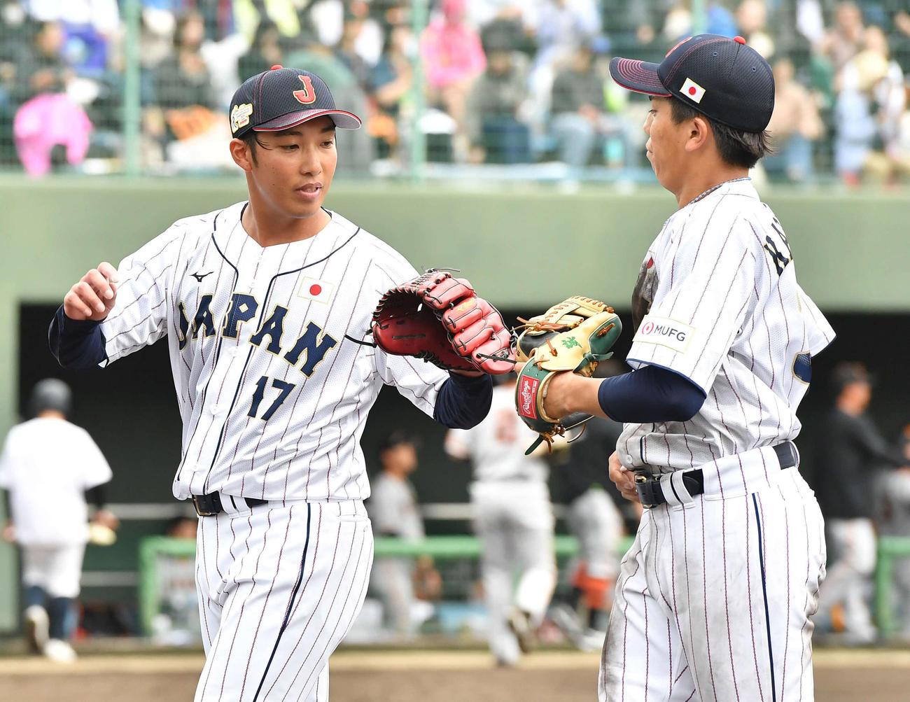 23年11月10日　侍ジャパン対巨人　3回裏を終え、門脇（右）とグラブタッチを交わしながらベンチへ戻る侍ジャパン赤星（撮影・岩下翔太）