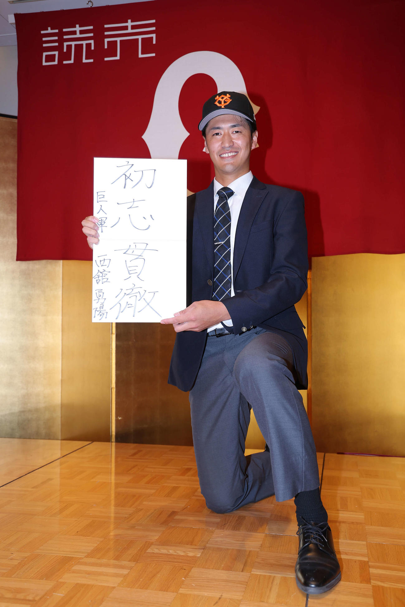 巨人の仮契約を終え、「初志貫徹」としたためた色紙を手に写真に納まる中大・西舘（撮影・河田真司）