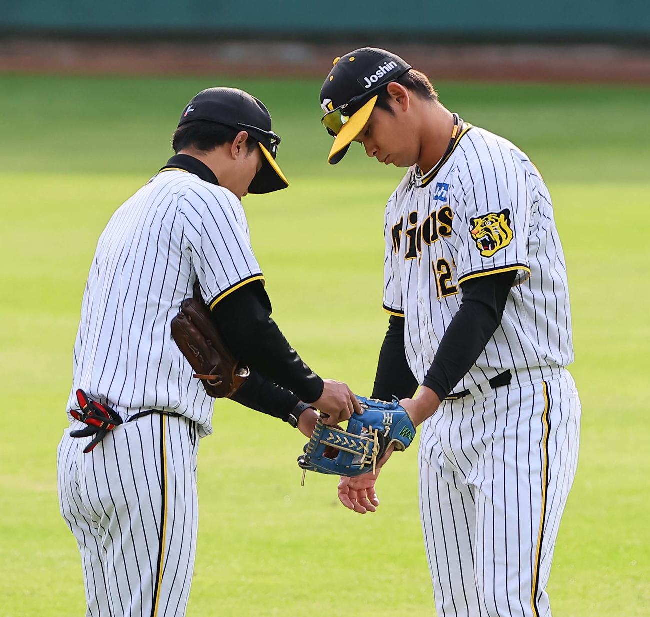 早出特守を行う野口（右）上本コーチからグラブの使い方を教わる（撮影・上田博志）