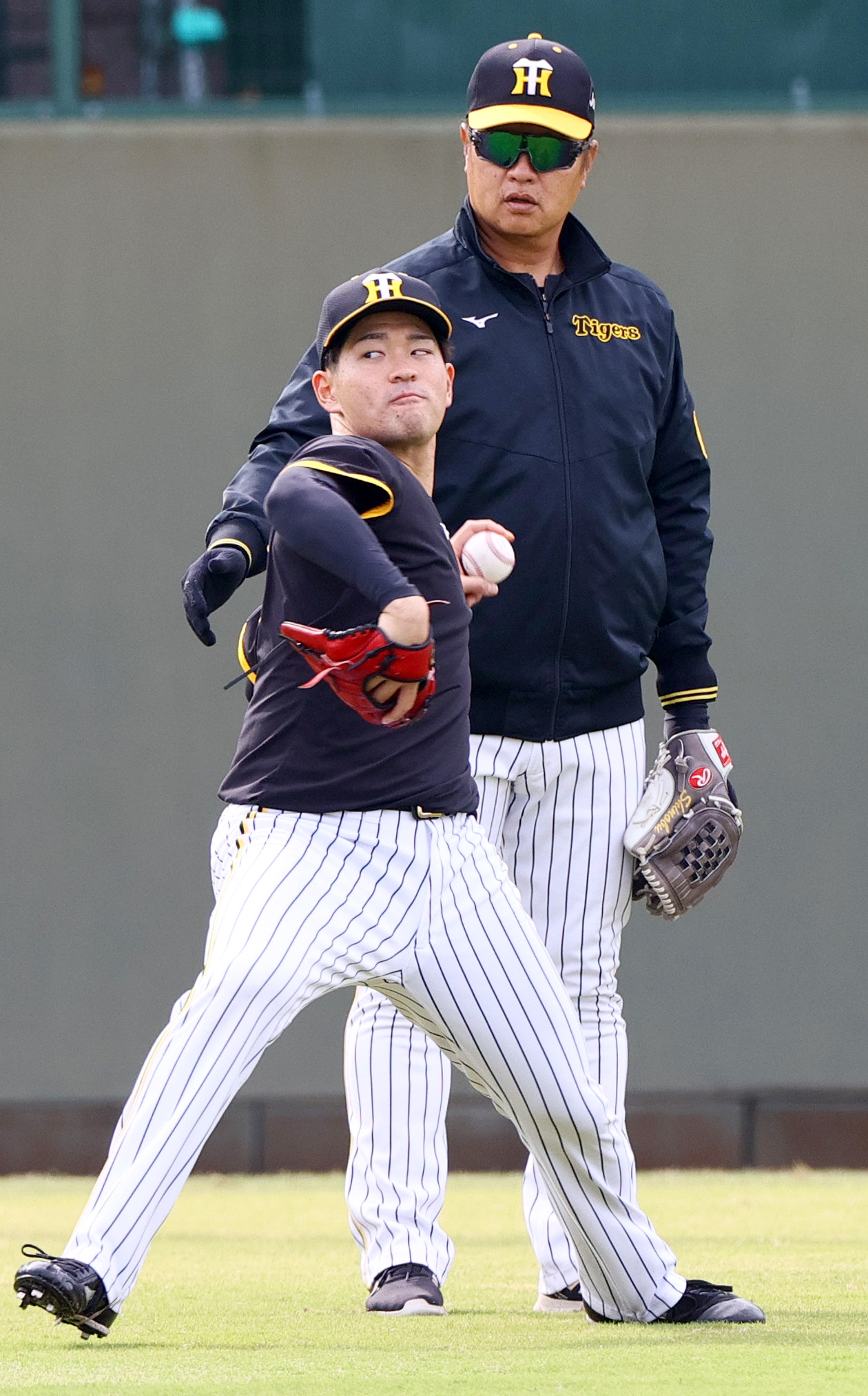鳴尾浜で伊藤稜（手前）は福原2軍投手コーチの指導を受けながら投球する（撮影・上山淳一）