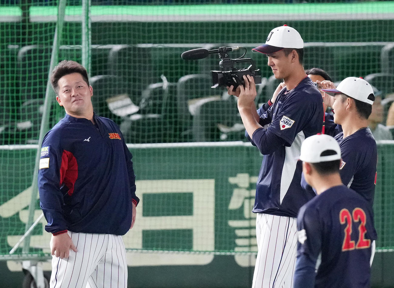 日本対韓国　試合前の練習中に牧（左）を撮影する秋広（左から2人目）（撮影・菅敏）