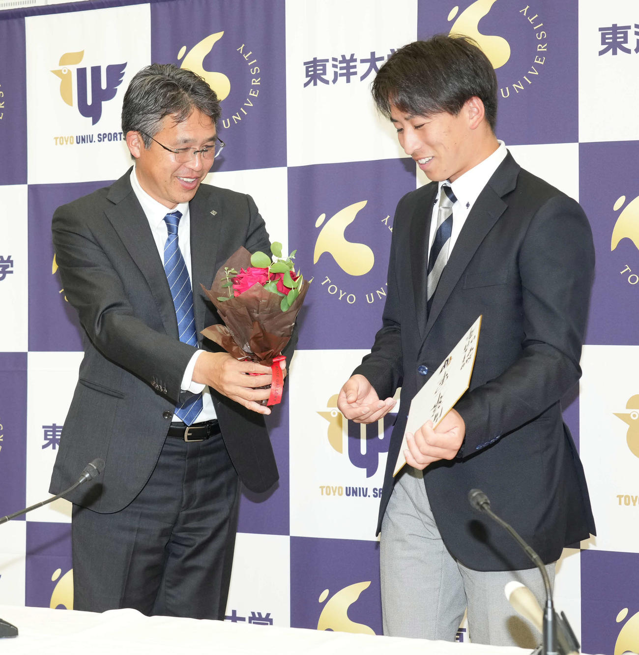 日本ハム1位指名を受けた東洋大・細野は仮契約を終え大渕スカウト部長（左）からバラの花束を贈呈され笑顔を見せる（撮影・小沢裕）