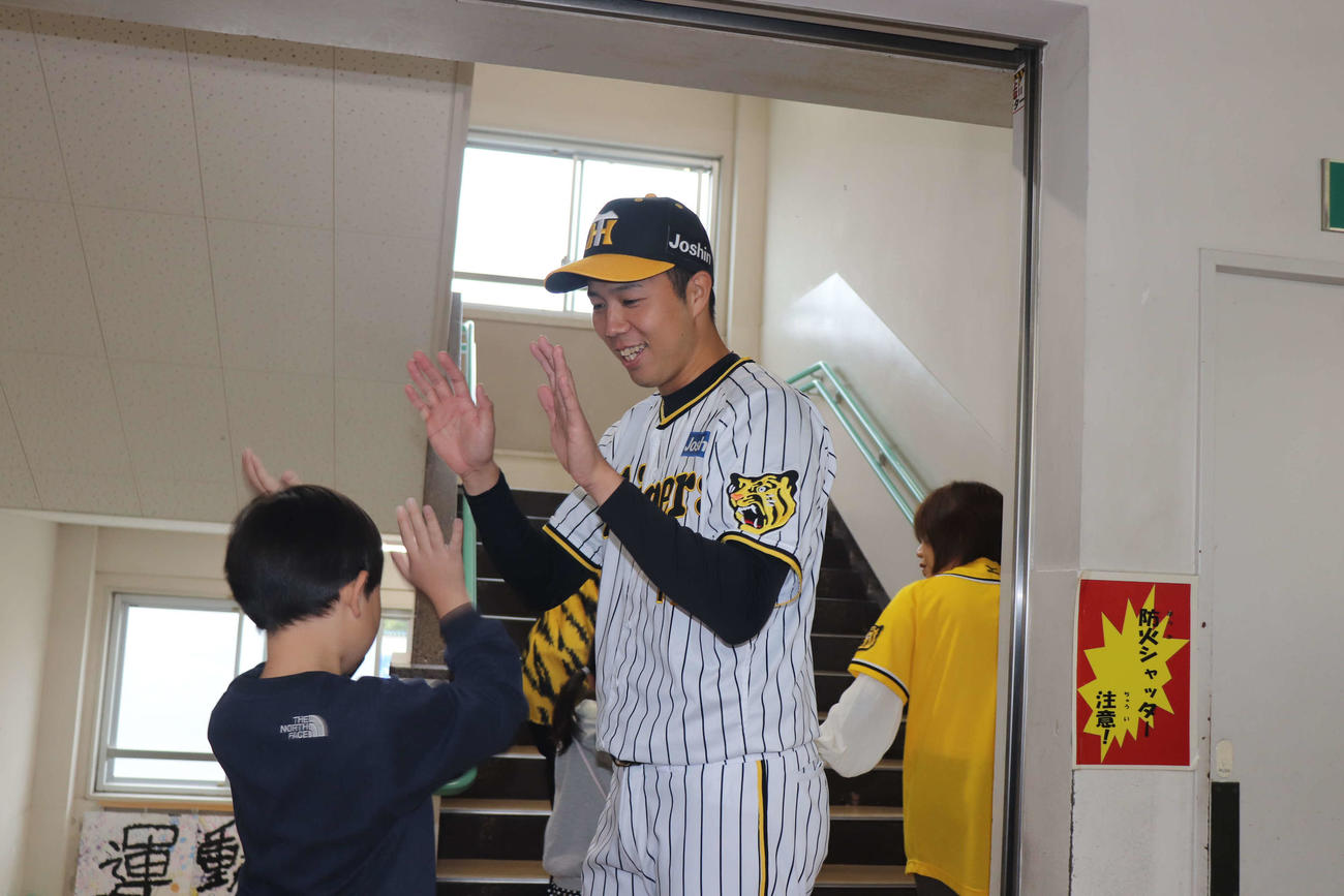訪問先の小学校で子どもたちとハイタッチをかわす青柳