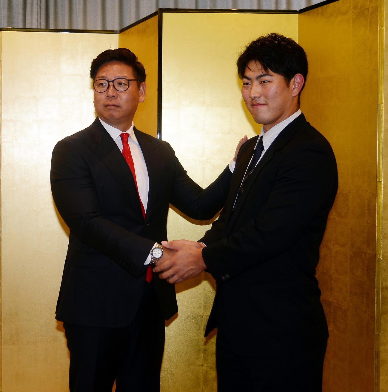 担当の松本スカウト（左）と握手を交わす静岡大・佐藤