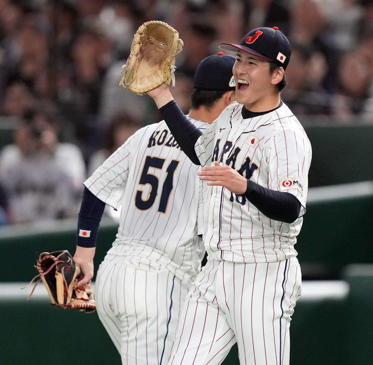 日本対韓国　7回表、味方の好守備で無失点に抑えた日本先発の隅田（手前）は、笑顔でナインとハイタッチ（撮影・たえ見朱実）