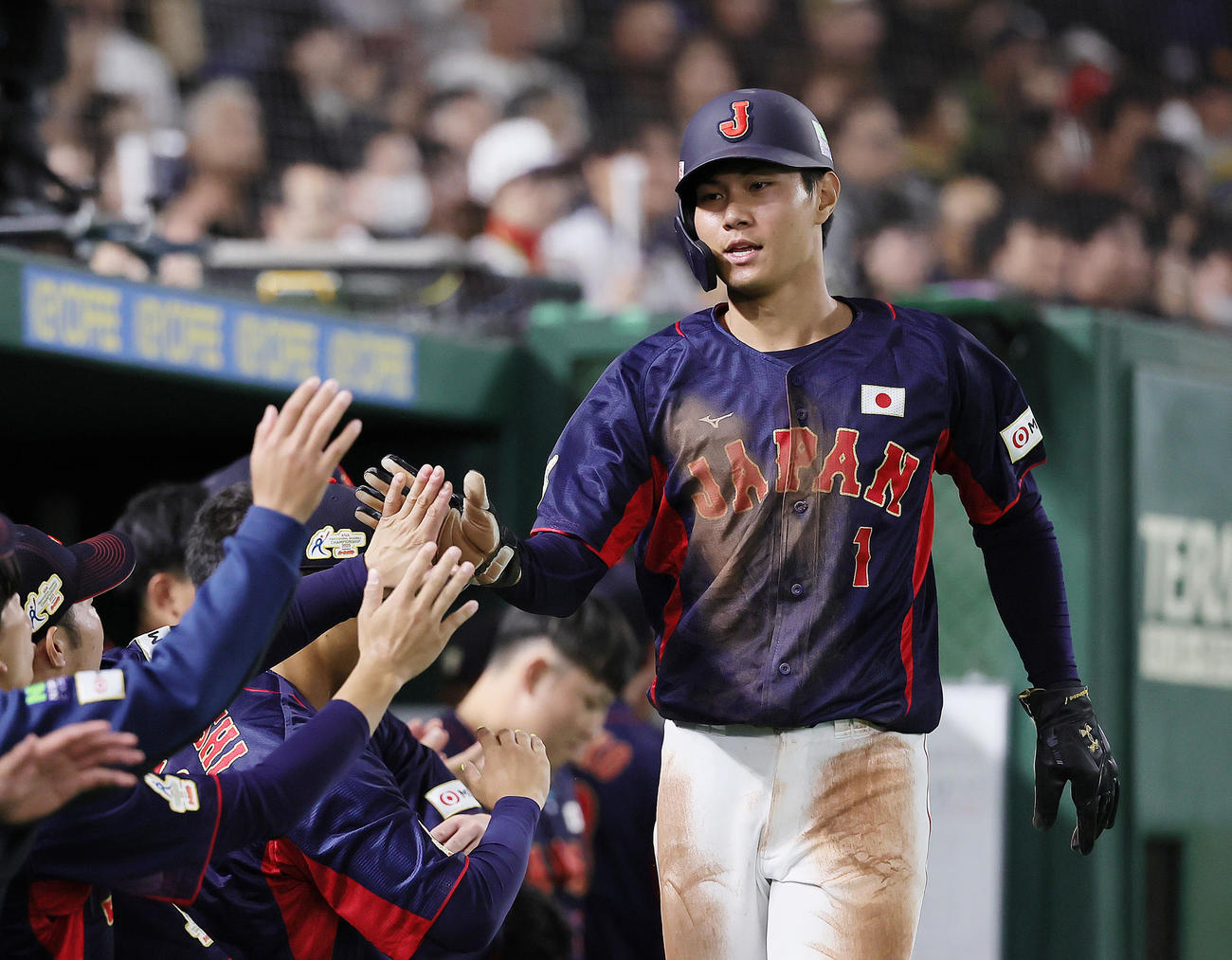 日本対オーストラリア　1回表日本無死一、二塁、小園の中前適時打で生還し、タッチを交わす藤原（撮影・足立雅史）