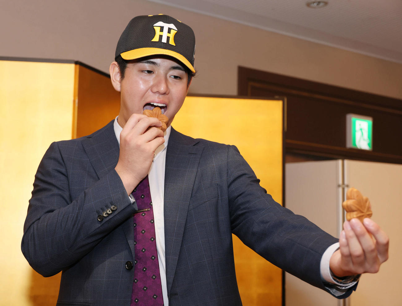 阪神との仮契約を済ませ、会見後にもみじまんじゅうを頬張るドラフト5位、JR西日本の石黒選手（撮影・加藤孝規）