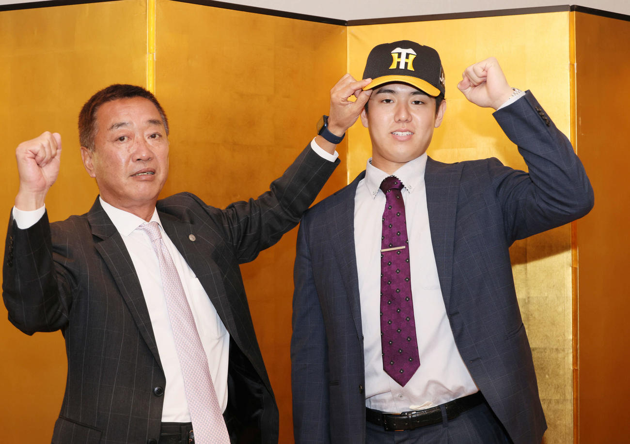 阪神との仮契約を済ませ、山本スカウト（左）に帽子をかぶせてもらうJR西日本・石黒（撮影・加藤孝規）