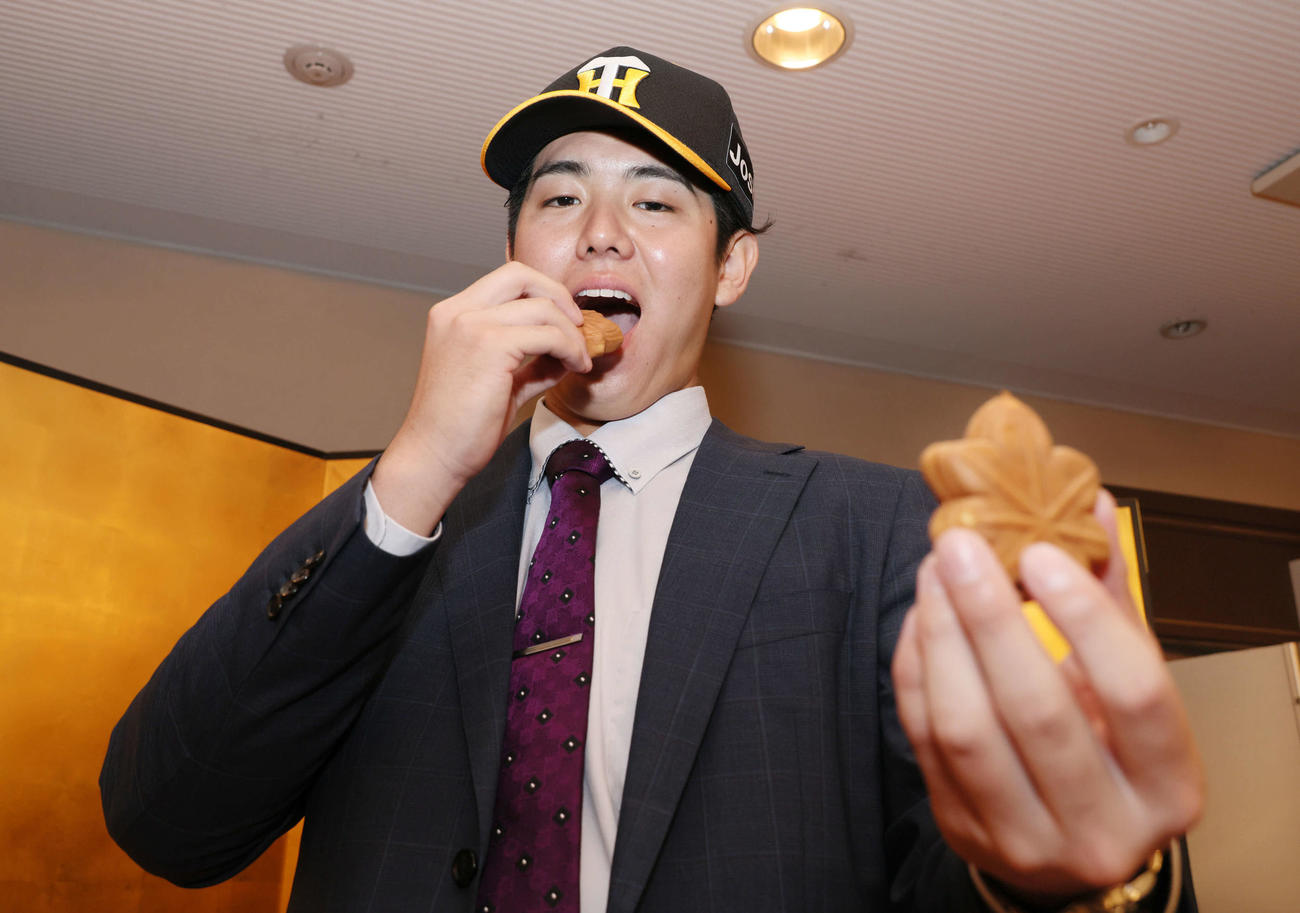 阪神との仮契約を済ませ、もみじまんじゅうを頬張るJR西日本・石黒（撮影・加藤孝規）