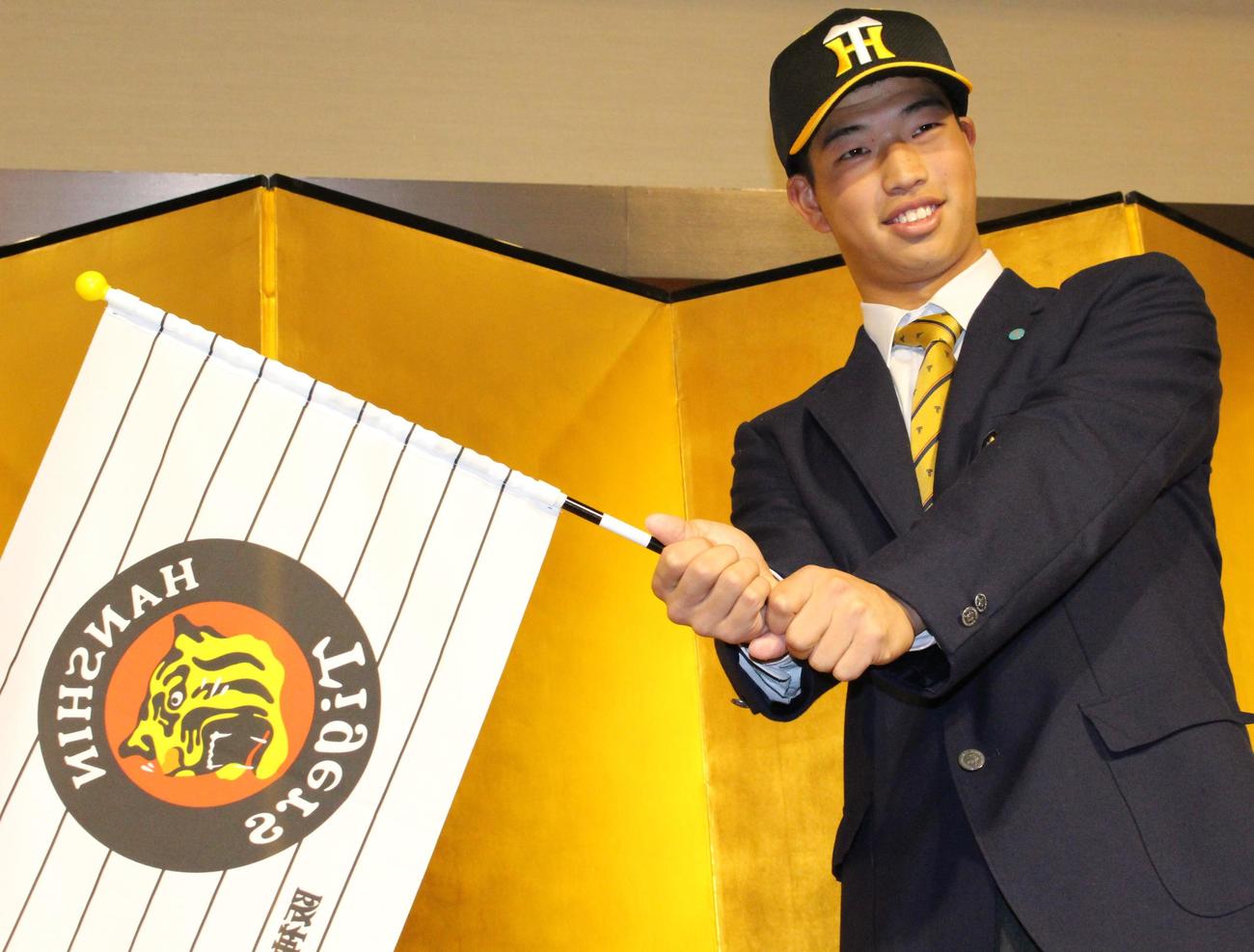 仮契約交渉を終え、旗を振る阪神ドラフト4位の東海大熊本星翔・百崎（撮影・菊川光一）