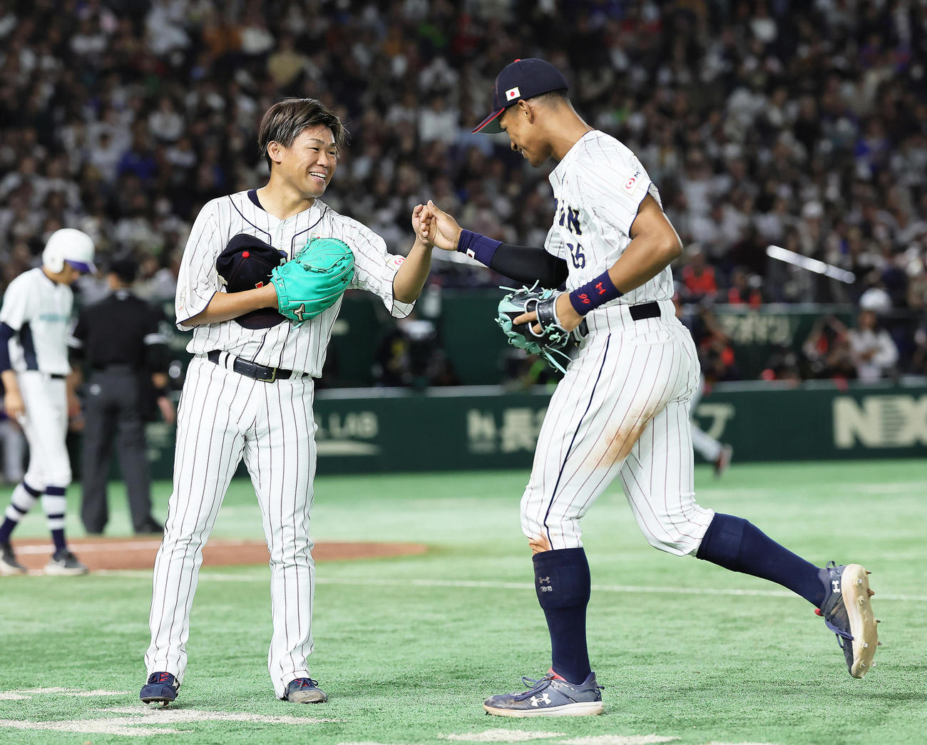 日本対韓国　9回、好捕を見せた万波（右）とタッチを交わす田口（撮影・足立雅史）
