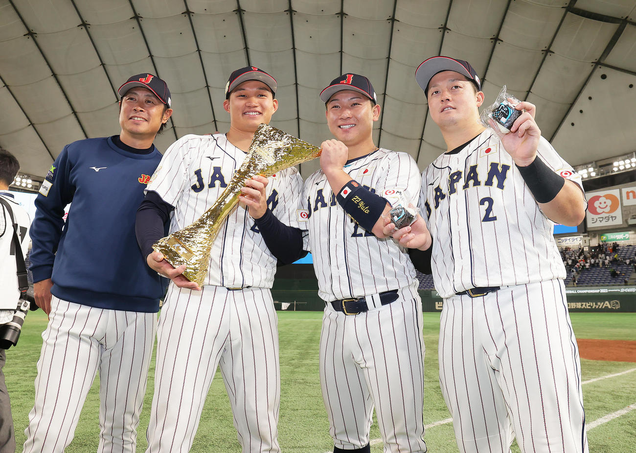 日本対韓国　優勝の記念撮影に笑顔を見せる、左から亀井コーチ、森下、古賀、牧（撮影・足立雅史）