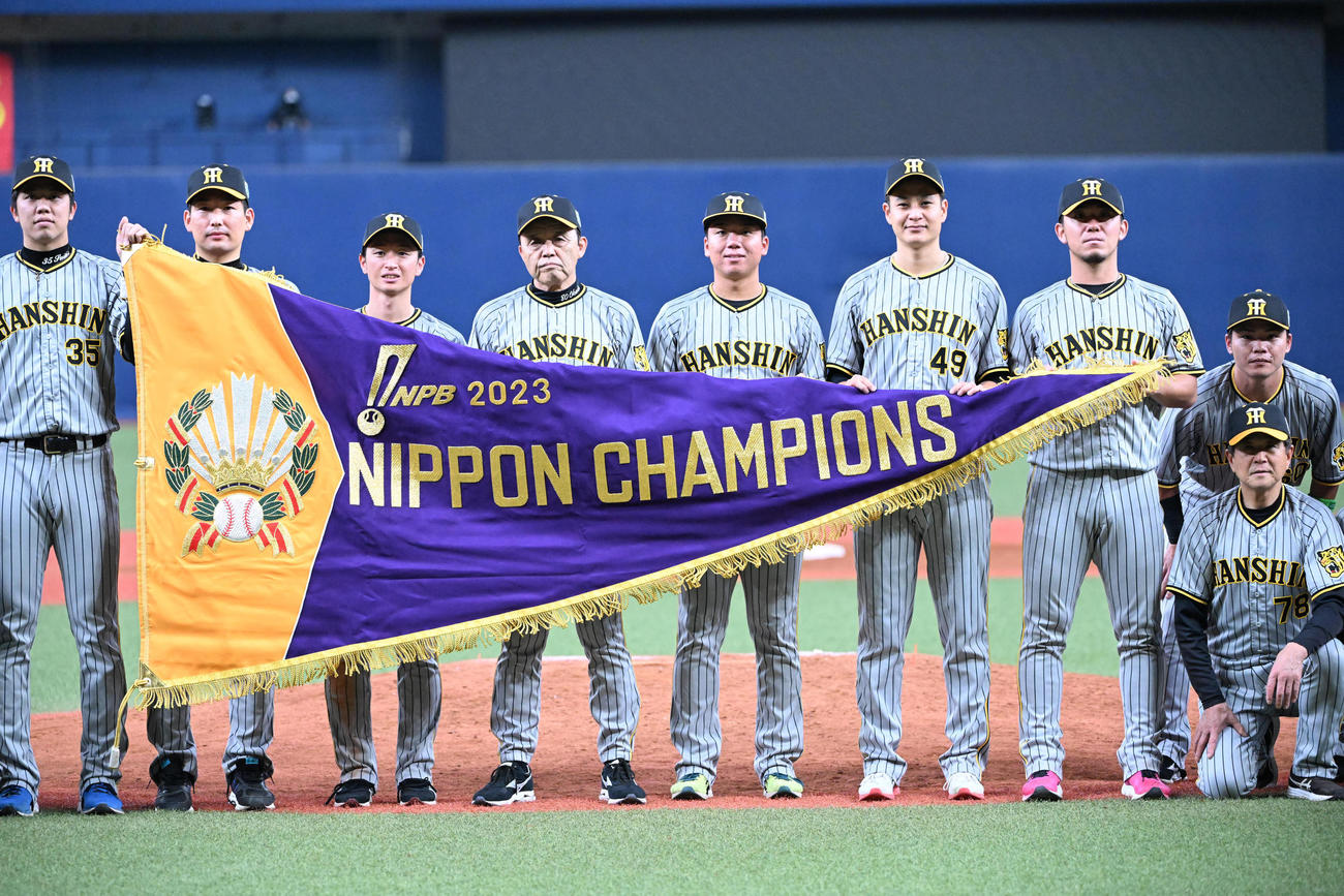 日本一に輝き、優勝旗を掲げる岡田彰布監督ら（2023年11月5日撮影）