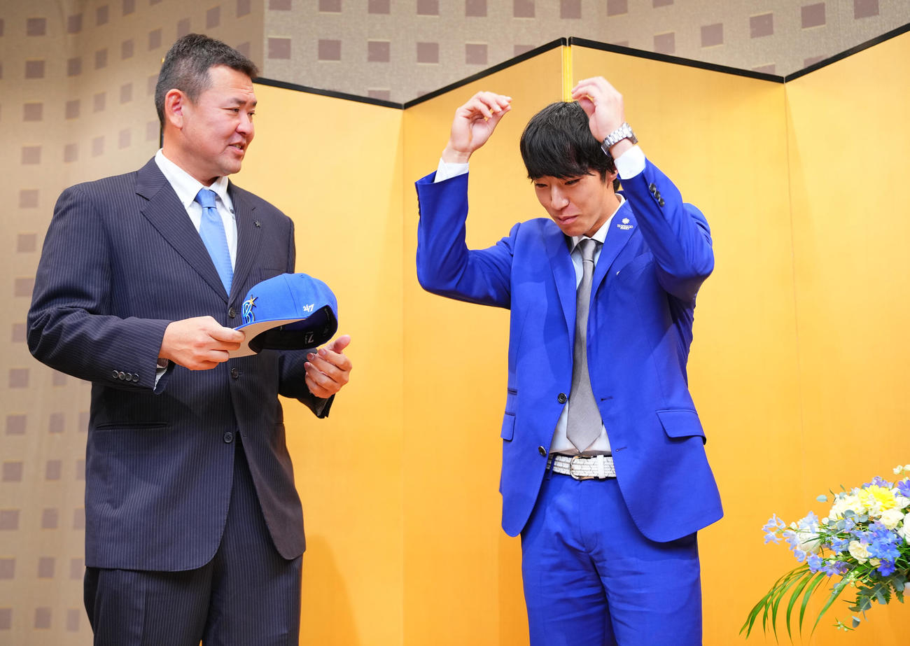 契約を終えDeNA度会（右）は横山スカウトにフォトセッションで帽子をそっと被せるようお願いする（撮影・垰建太）