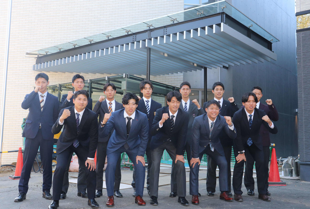 新しいジャイアンツ寮の前で記念撮影する巨人の新人選手たち。前列左から泉口、森田、西舘、佐々木、又木、後列左から平山、園田、宇都宮、三浦、村山、田上、千葉（撮影・小早川宗一郎）