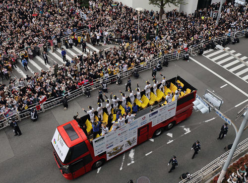 大勢のファンの歓声を受けながら神戸でVパレードをする岡田監督（左上）が乗る1号車と阪神ナイン（撮影・上田博志）