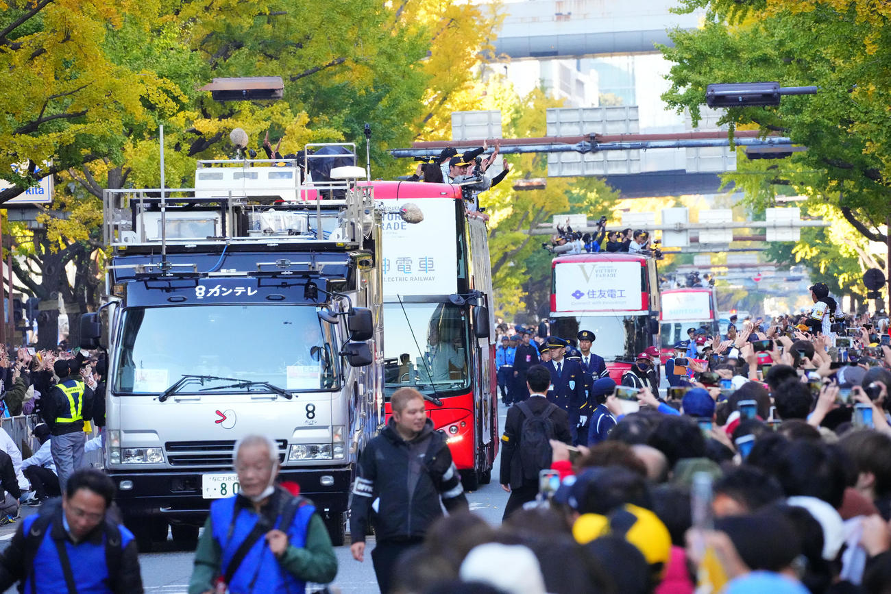 優勝パレードで、沿道のファンに手を振る阪神の選手ら（撮影・藤尾明華）