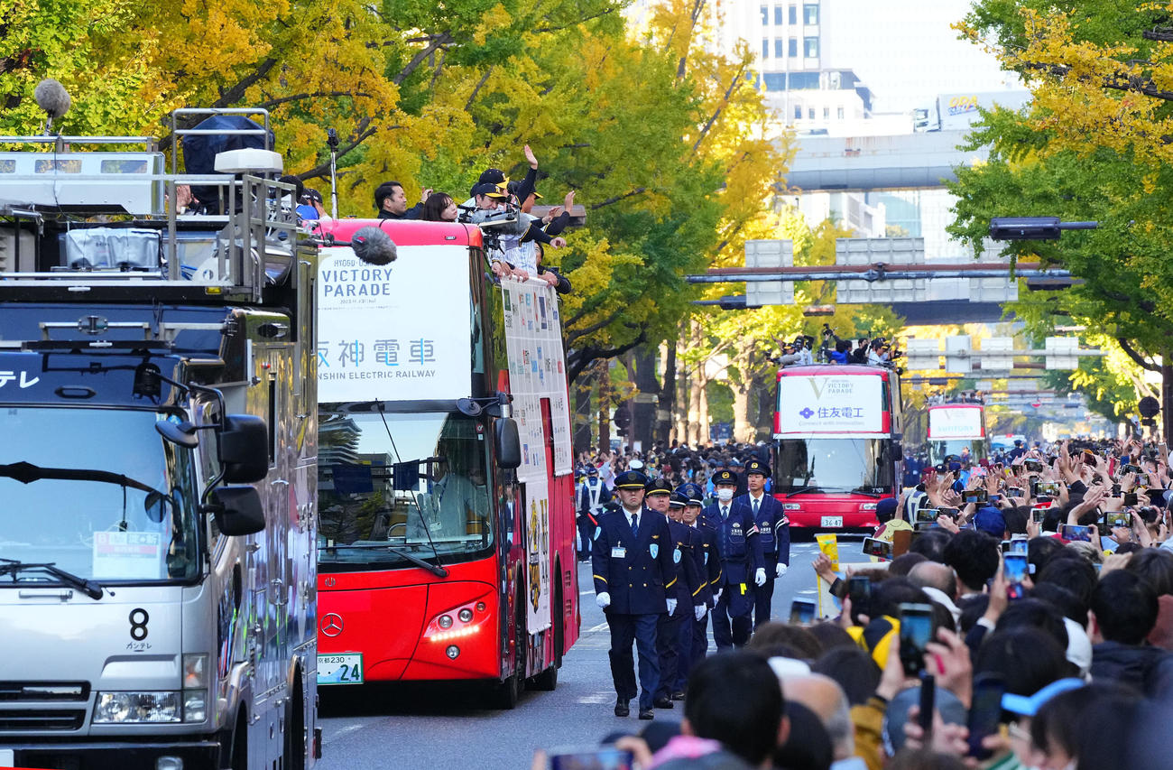 優勝パレードで、沿道のファンに手を振る阪神の選手ら（撮影・藤尾明華）