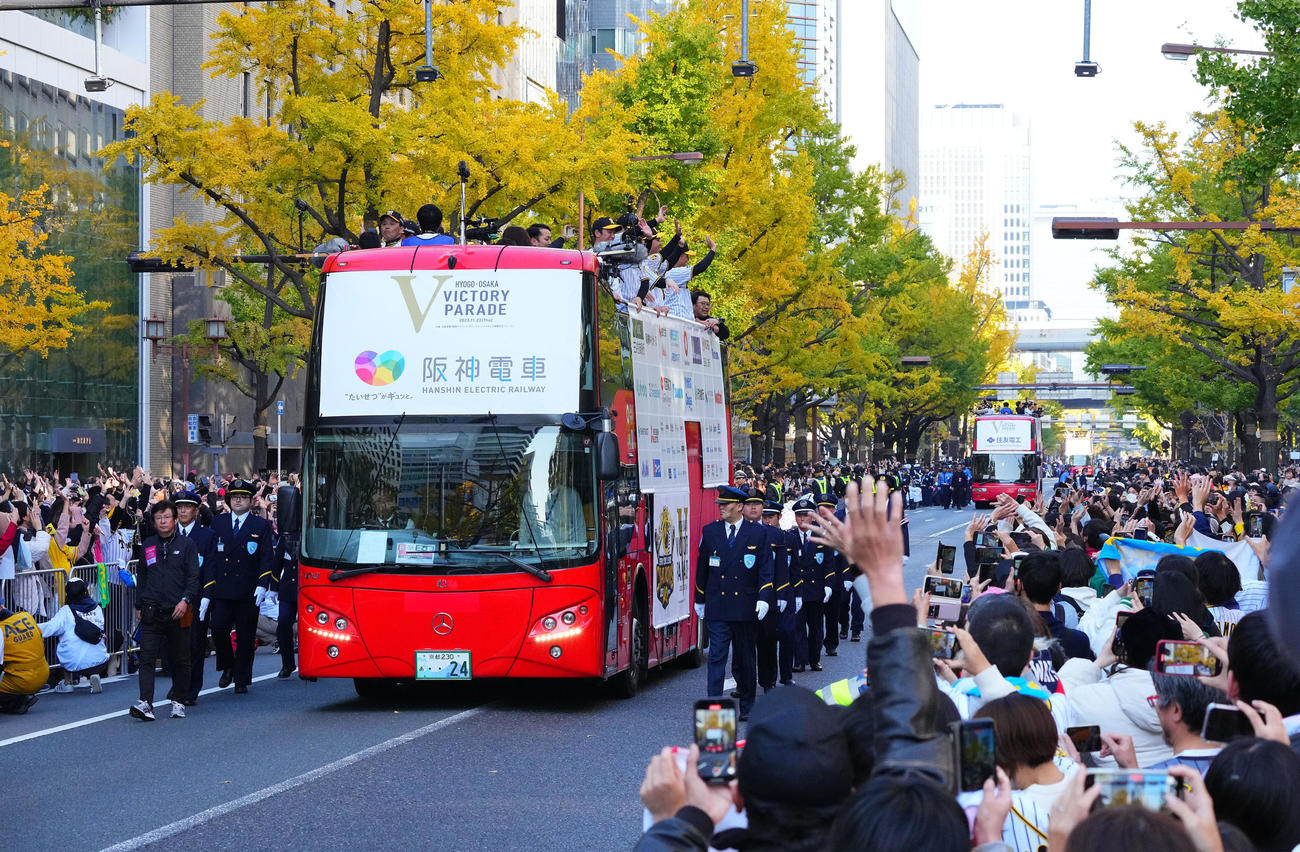 優勝パレードで、沿道のファンに手を振る阪神の選手ら（撮影・藤尾明華）