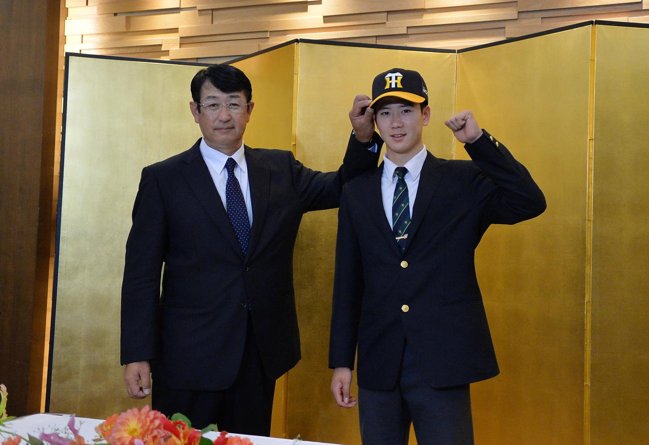 阪神の帽子を被り、笑顔でガッツポーズする仙台育英・山田（右）と葛西スカウト（撮影・濱本神威）