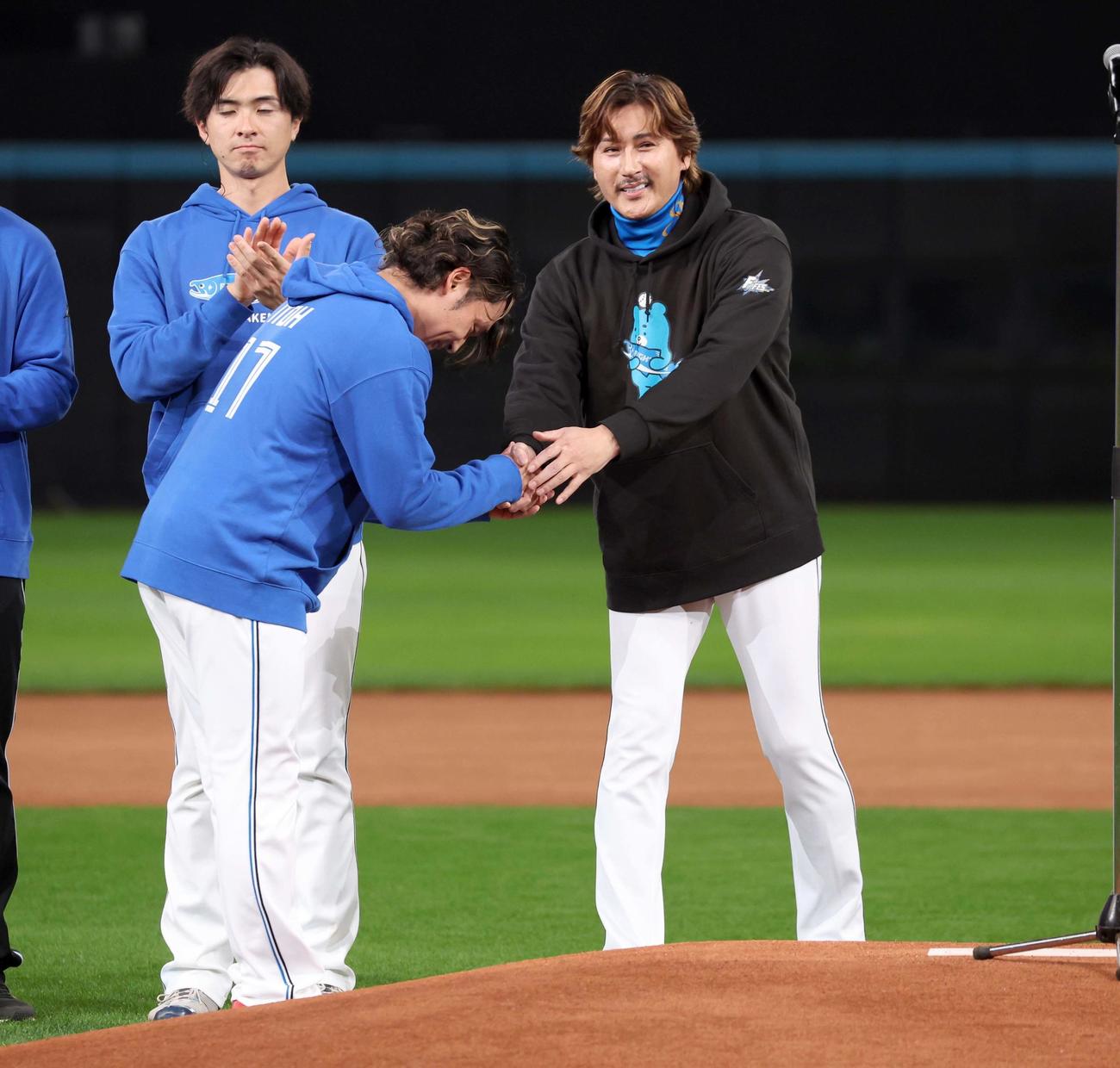 来季の開幕投手に指名された伊藤（左）は新庄監督と握手する（撮影・黒川智章）