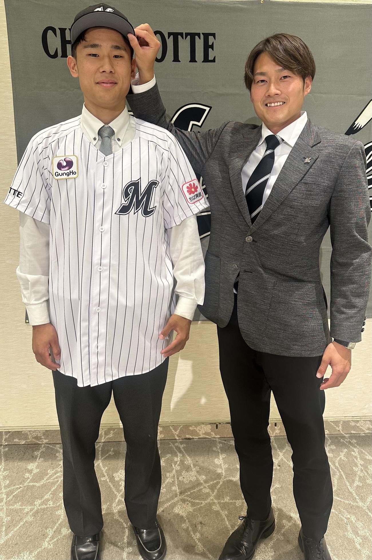 契約を終え、有吉担当スカウト（右）に帽子をかぶせてもらうロッテの育成ドラフト4位、延岡学園・藤田和樹外野手