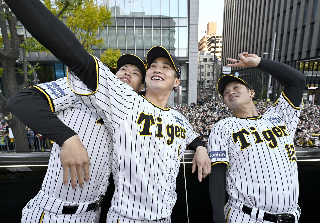 大阪・御堂筋での優勝パレードで、自撮りする阪神（左から）佐藤輝、木浪、坂本（代表撮影）