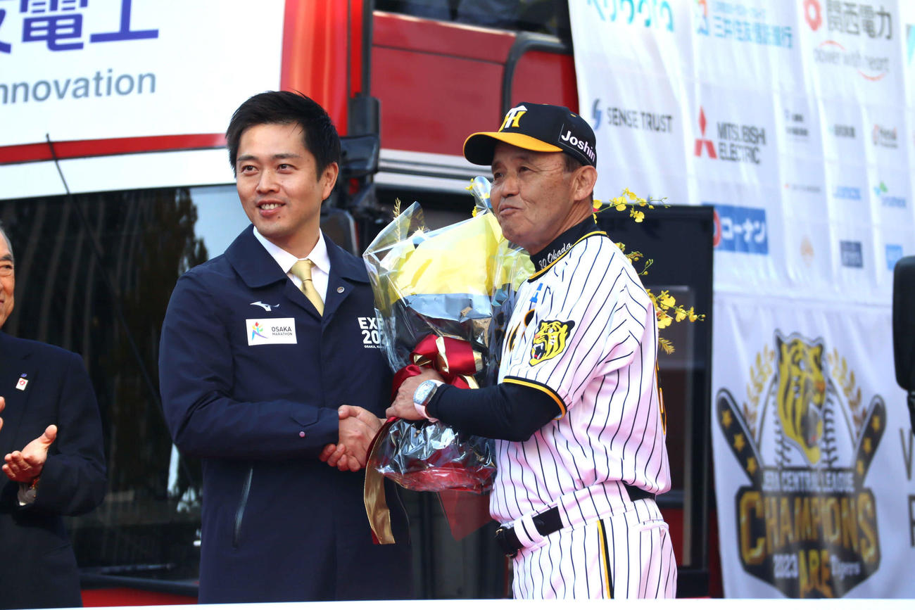 オープニングセレモニーの花束贈呈で握手を交わす、吉村大阪府知事（左）と阪神岡田監督（撮影・村松万里子）