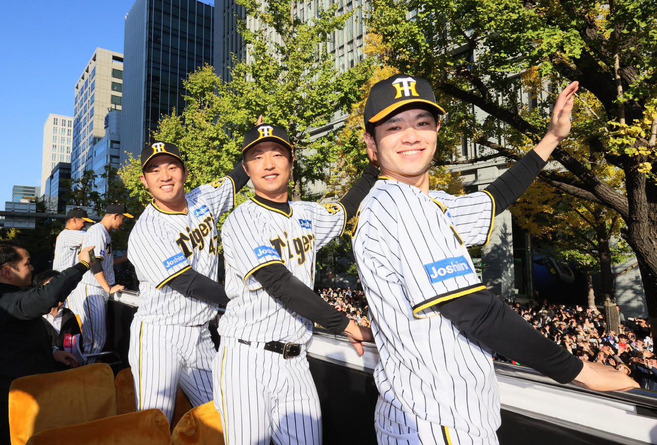 沿道に詰めかけたファンに手を振って応える阪神の右から中野、島本、桐敷（代表撮影）