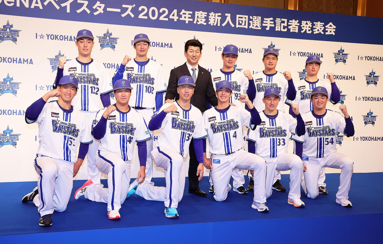 DeNA三浦監督（後方中央左）を囲み記念撮影に臨む新入団選手たち。前列左からドラフト6位井上、ドラフト4位石上、ドラフト2位松本、ドラフト1位度会、ドラフト3位武田、ドラフト5位石田、後列左から育成4位庄司、育成2位清水、1人おいて育成1位高見沢、育成3位小笠原、育成5位近藤（撮影・足立雅史）