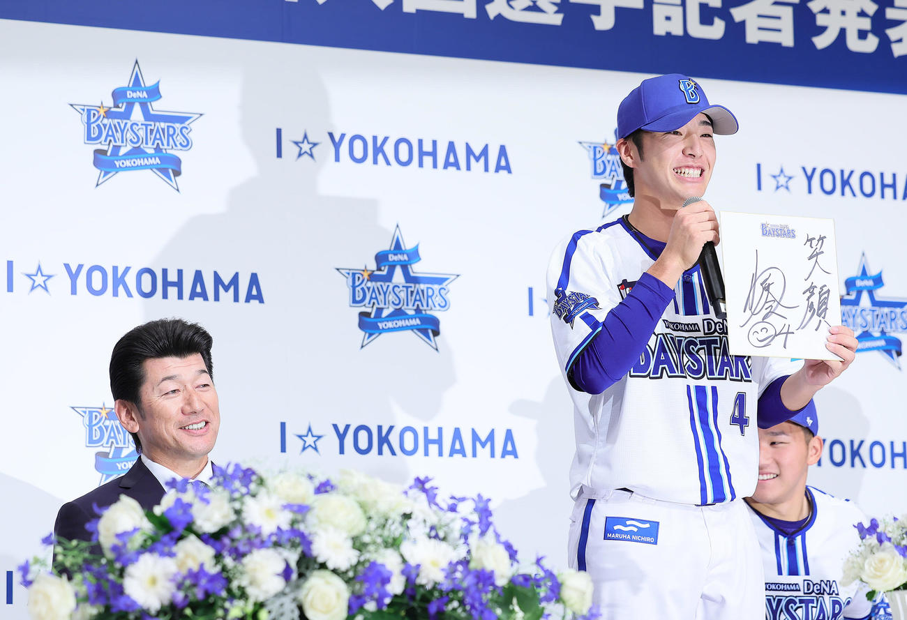 DeNA新入団選手発表会に臨んだドラフト1位の度会（右）は色紙に笑顔と記す。左は三浦監督（撮影・足立雅史）
